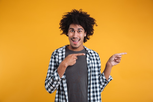 Portrait of a cheerful young african man pointing fingers away