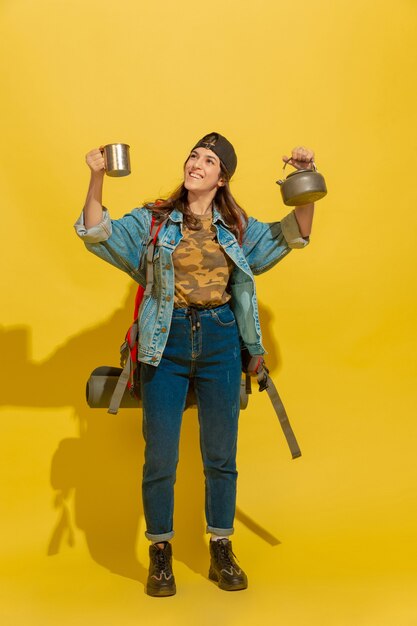 Portrait of a cheerful young caucasian tourist girl isolated on yellow