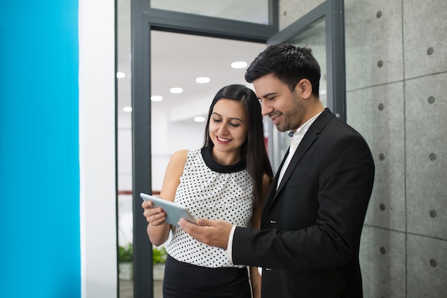 Portrait of cheerful young colleagues browsing on digital tablet