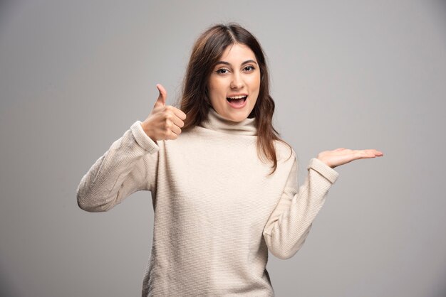 Portrait of a cheerful young girl showing a thumb up .