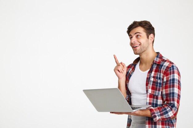 Portrait of a cheerful young man holding laptop computer