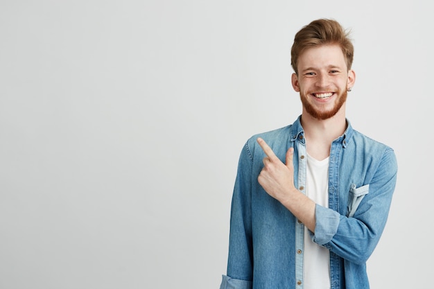 Portrait of cheerful young man smiling pointing finger up.