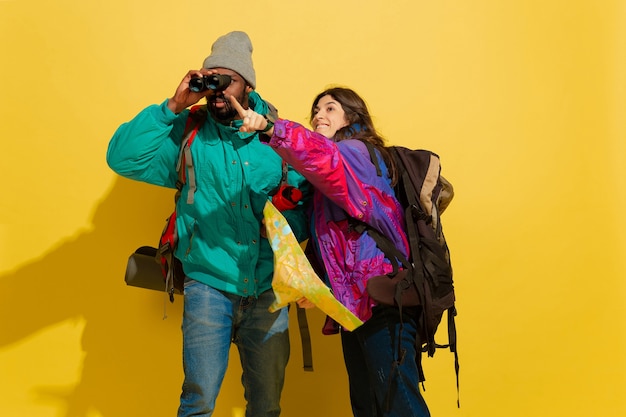 Foto gratuita ritratto di una giovane coppia di turisti allegri isolati su giallo