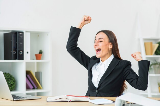 Portrait of cheering young businesswoman clenching her fist