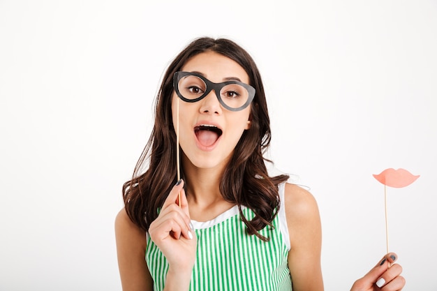 Free photo portrait of a cheery girl holding paper eyeglasses