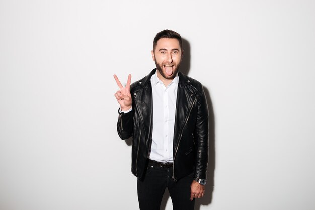 Portrait of a cheery man in jacket showing peace gesture