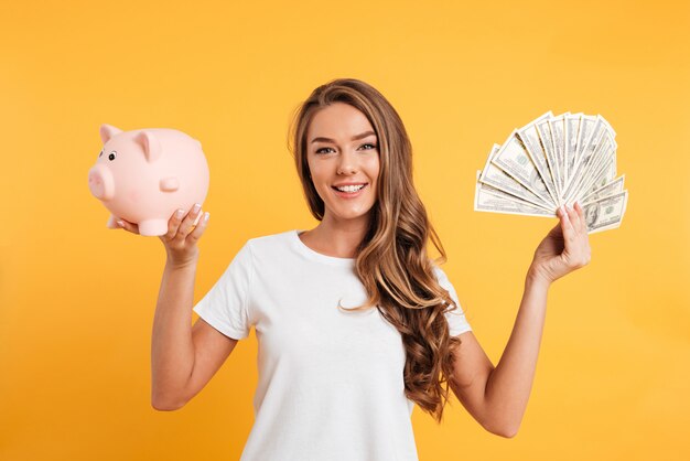 Portrait of a cheery young girl holding piggy bank