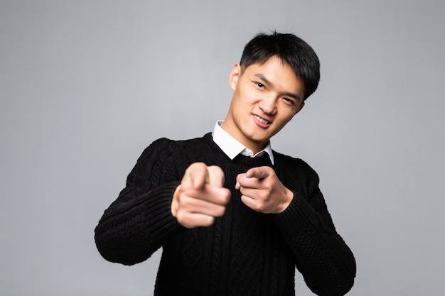Portrait of chinese man points finger at you over isolated white wall