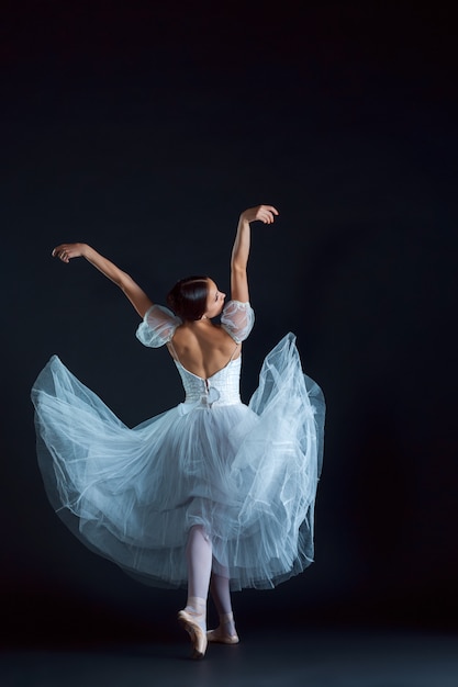 Portrait of classical ballerina in white dress on black