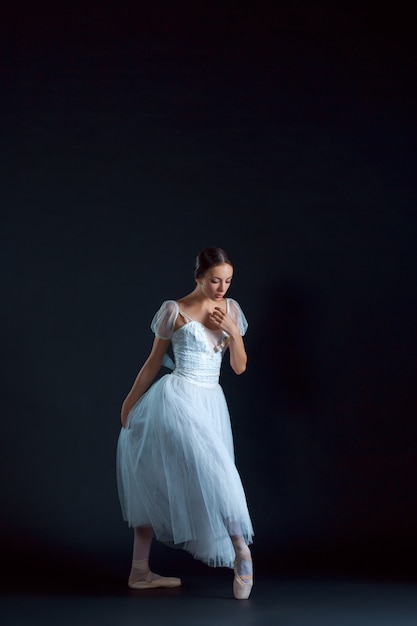 Portrait of the classical ballerina in white dress on black