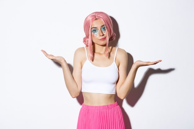 Portrait of clueless beautiful young woman shrugging, standing unaware in halloween costume with pink hair