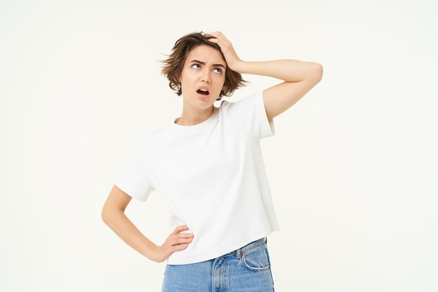 Free photo portrait of complicated woman touches her head looking up puzzled by something feeling distressed