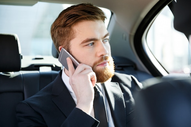 Портрет сконцентрированного бизнесмена говоря на мобильном телефоне
