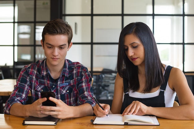 Portrait of concentrated student girl and boy sitting at desk