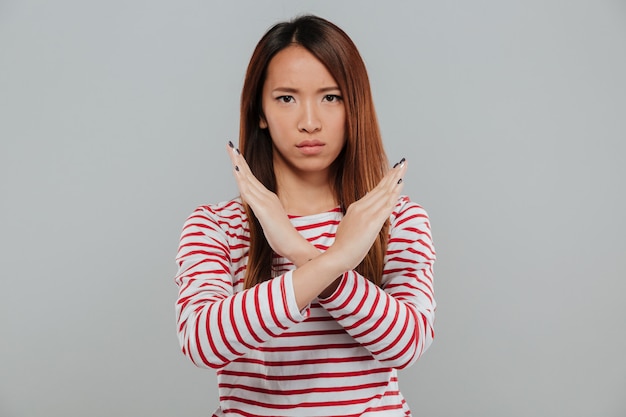 Foto gratuita ritratto di una donna asiatica sicura che mostra gesto di mano attraversato