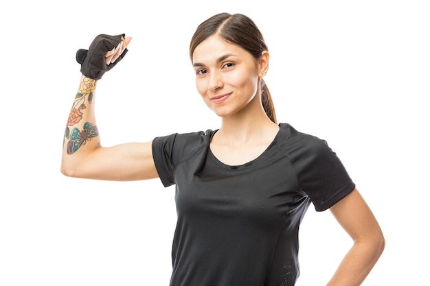 Portrait of confident athletic female flexing her biceps over white background