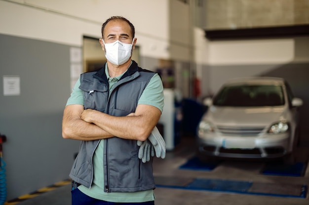 Portrait of confident auto mechanic wearing face mask at his repair shop