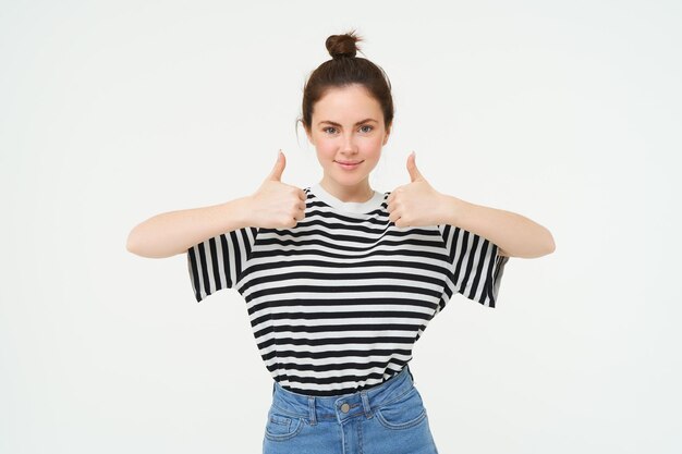 Free photo portrait of confident beautiful woman showing thumbs up recommends product likes and approves stands