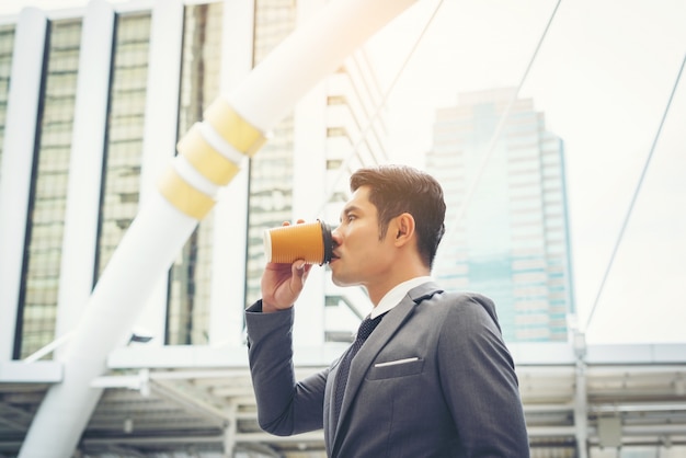 屋外でコーヒーを飲む自信のあるビジネスマンの肖像