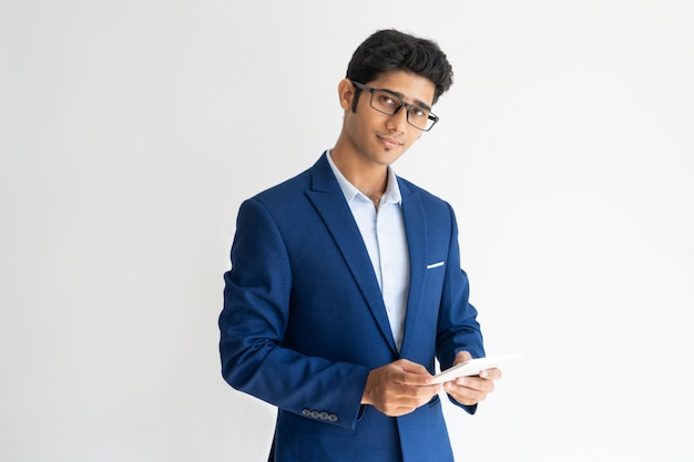 Portrait of confident businessman in glasses with smartphone.