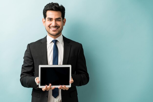 Портрет уверенного в себе бизнесмена, улыбающегося, держа в руках цифровой планшет с пустым экраном на изолированном фоне