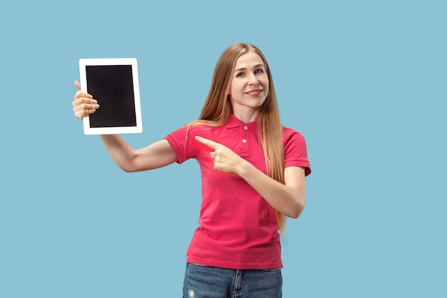 Portrait of a confident casual woman showing blank screen of laptop isolated wall