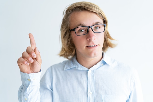 Portrait of confident guy in glasses showing attention gesture