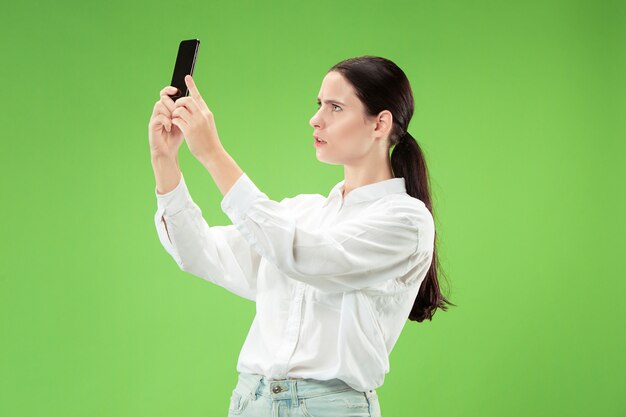 휴대 전화로 셀카 사진을 만드는 자신감이 행복 웃는 캐주얼 여자의 초상화