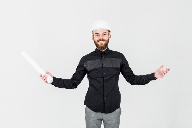 Portrait of confident male architect holding blueprint against white backdrop