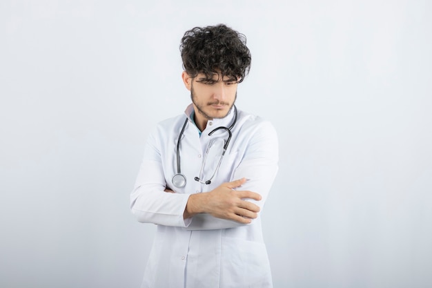 Ritratto di un medico maschio sicuro che guarda giù isolato su bianco.