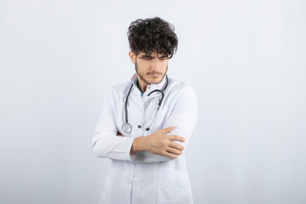 Portrait of a confident male doctor looking down isolated on white. 