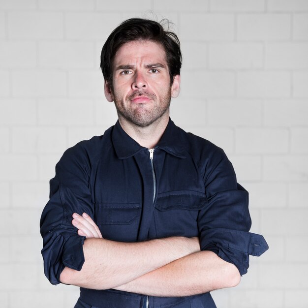 Portrait of confident male electrician standing against wall