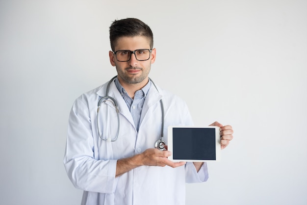 デジタルタブレットを見せている自信のある男性の医者の肖像画。