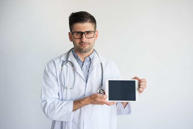 Портрет уверенно мужчины медика показывает цифровой планшет.