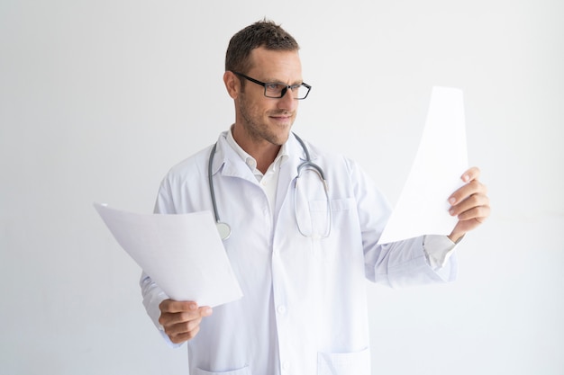 Portrait of confident mid adult doctor looking at documents.