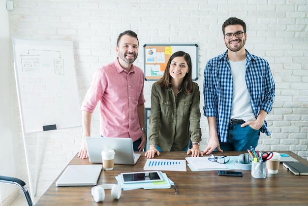 Portrait of confident professionals standing at conference table in meeting room at office