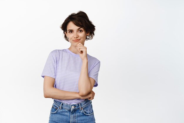 Portrait of confident smiling woman, smiling smug face and looking determined thoughtful, creative girl has a plan, standing against white background. Copy space