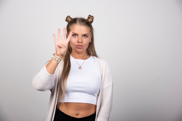 Portrait of confident woman with long hair showing her fingers.