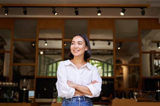 Portrait of confident young asian woman business owner cross arms on chest looking pleased standing 