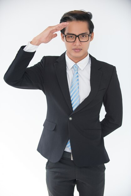 Portrait of confident young businessman saluting