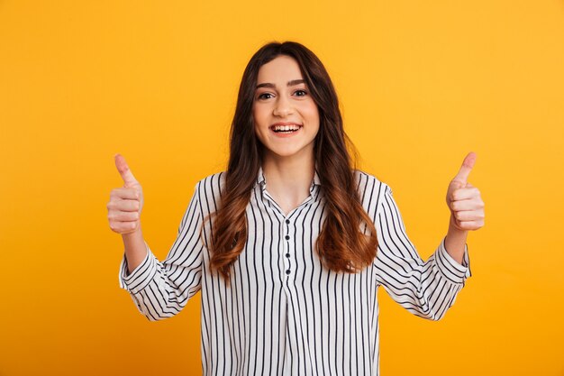 Portrait of a confident young girl showing two thumbs up