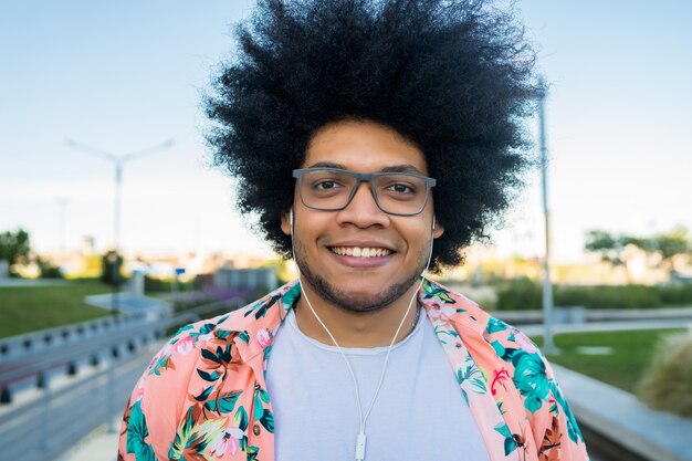 Portrait of confident young latin man smiling and looking while standing outdoors on the street. Urban concept.