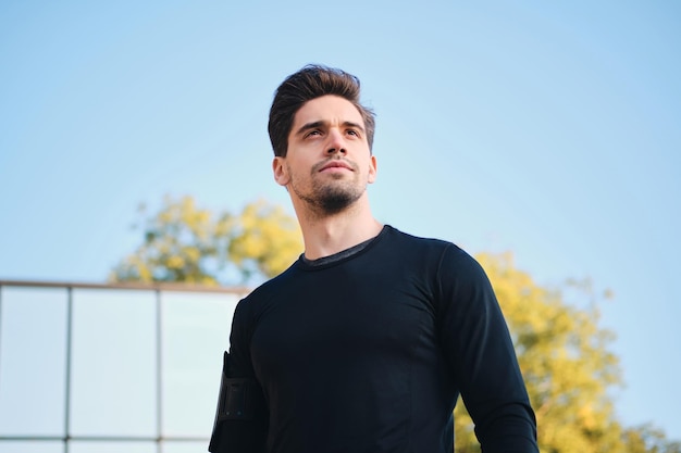 Free photo portrait of confident young man standing outdoor in city park and looking away