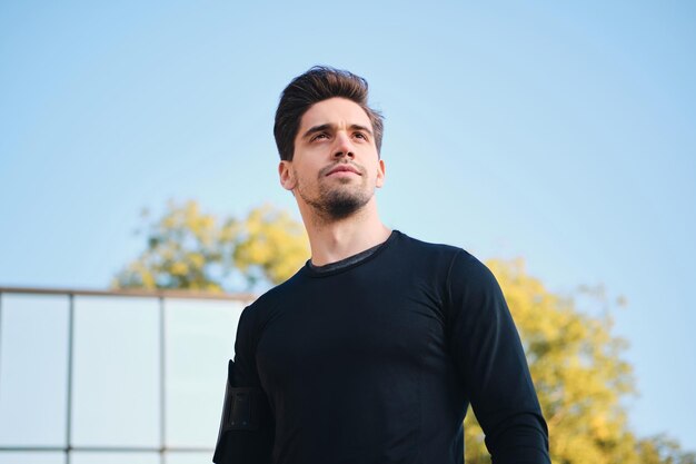 Portrait of confident young man standing outdoor in city park and looking away