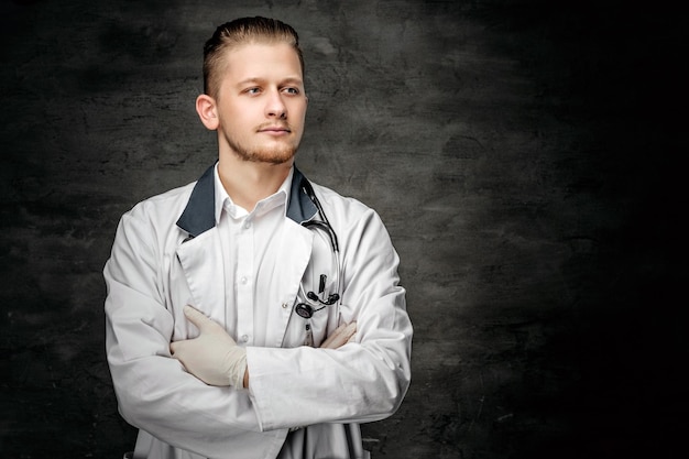 Портрет уверенного в себе молодого врача на сером фоне.