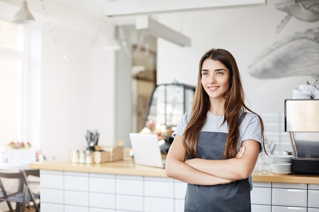 Foto gratuita ritratto di fiduciosa e giovane donna che possiede e gestisce un business di successo di pasticceria e caffè.