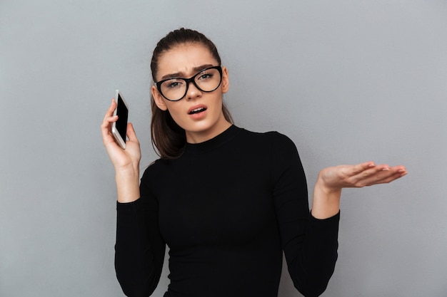 Portrait of a confused frustrated woman in eyeglasses