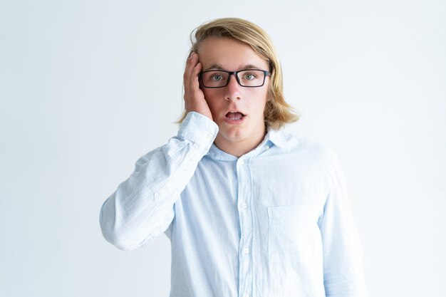 Портрет смущенный молодой студент-мужчина в очках
