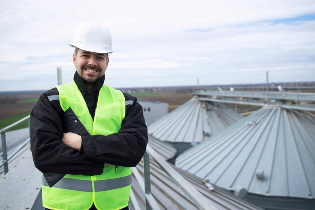 Portrait of construction worker standing on rooftops of high silos storage tanks