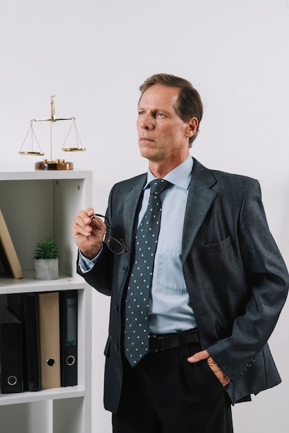 Free photo portrait of contemplated mature lawyer with hand in his pocket